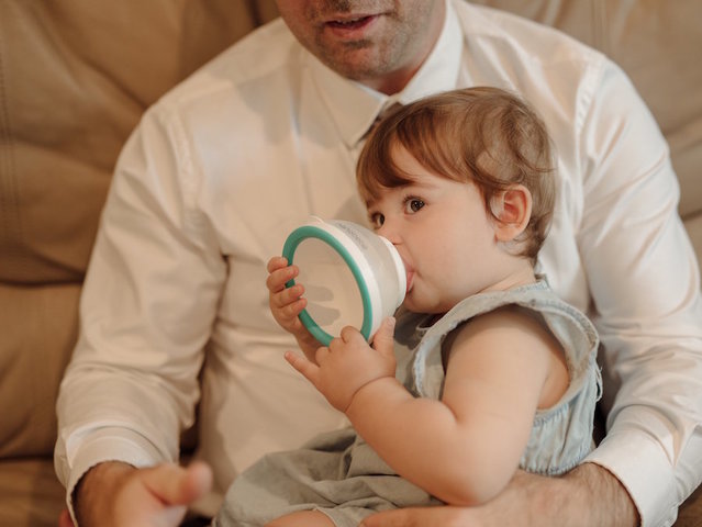 New style of baby bottle invented by tired dad with hungry infant waiting for warm breast milk